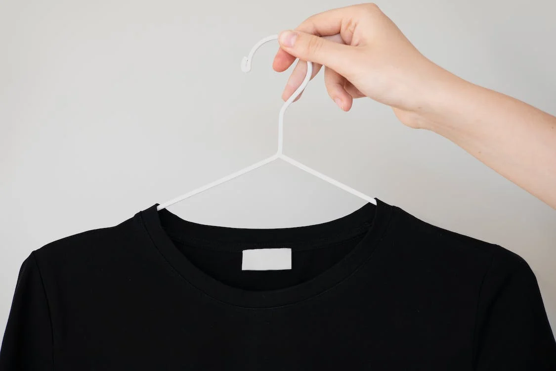 a black t-shirt hanging on a white clothes hanger