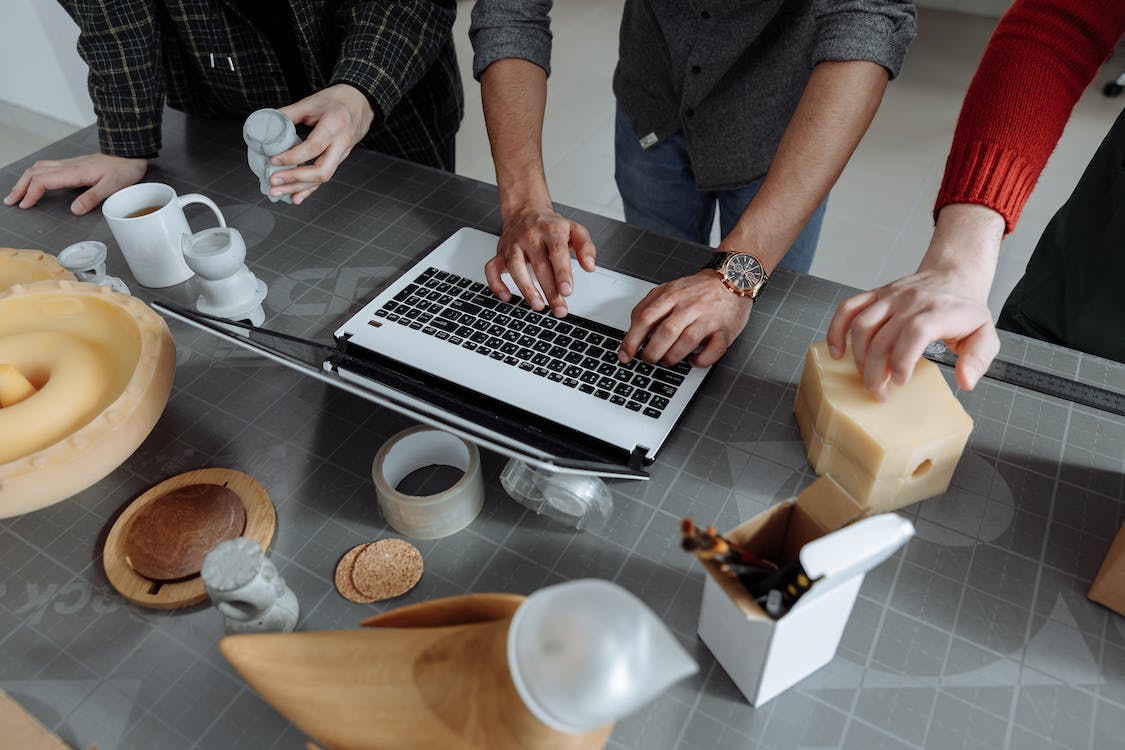 three people working at a laptop