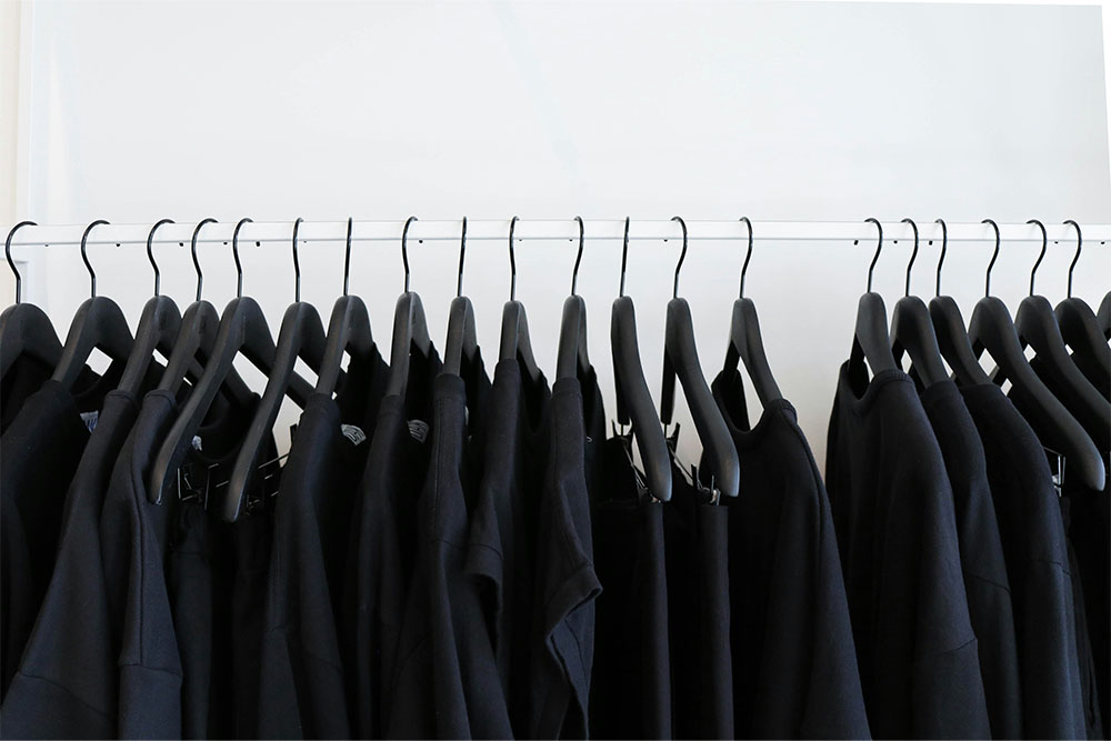 clothing rack with blank black tshirts on hangers lined up