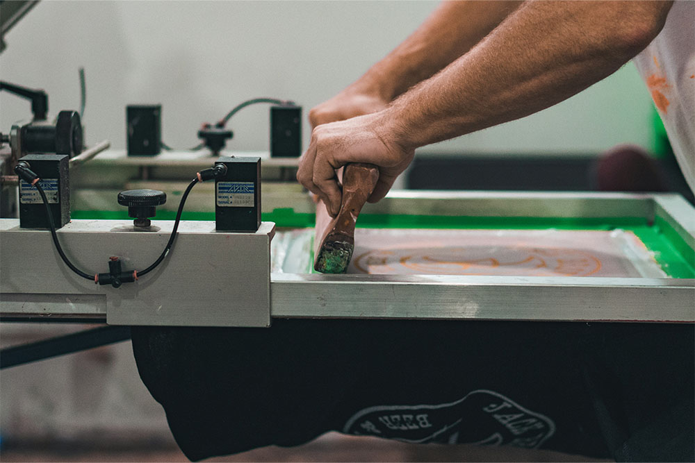 image of tshirt design being printed on tshirt with hands and printing machine