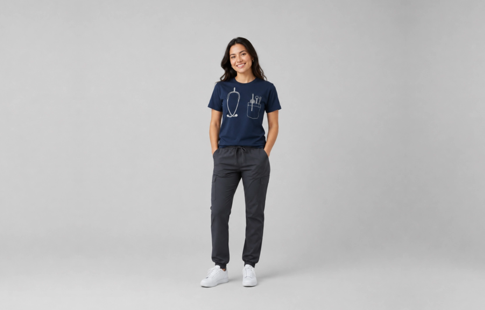 Smiling woman stands against a gray backdrop, wearing a navy T-shirt with medical sketch graphics and dark pants.