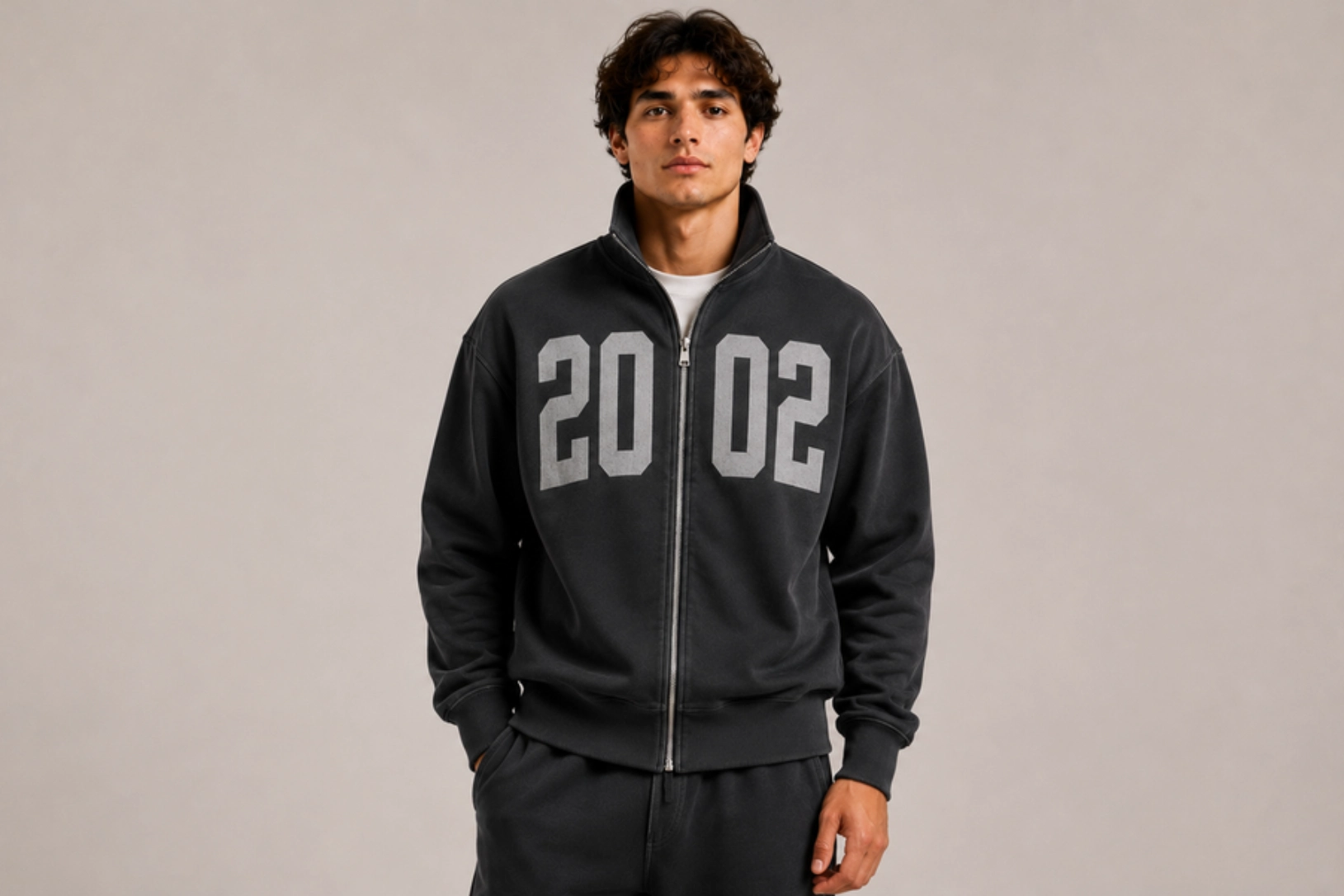 Young man standing in a black zip-up sweatshirt with large gray '2002' numbers on the front.