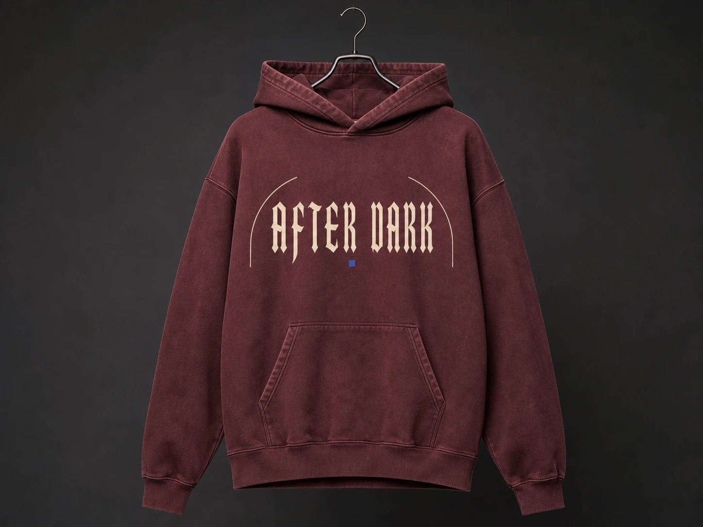 A maroon hoodie with "After Dark" text hangs on a hanger against a dark background, showcasing casual style and comfort.