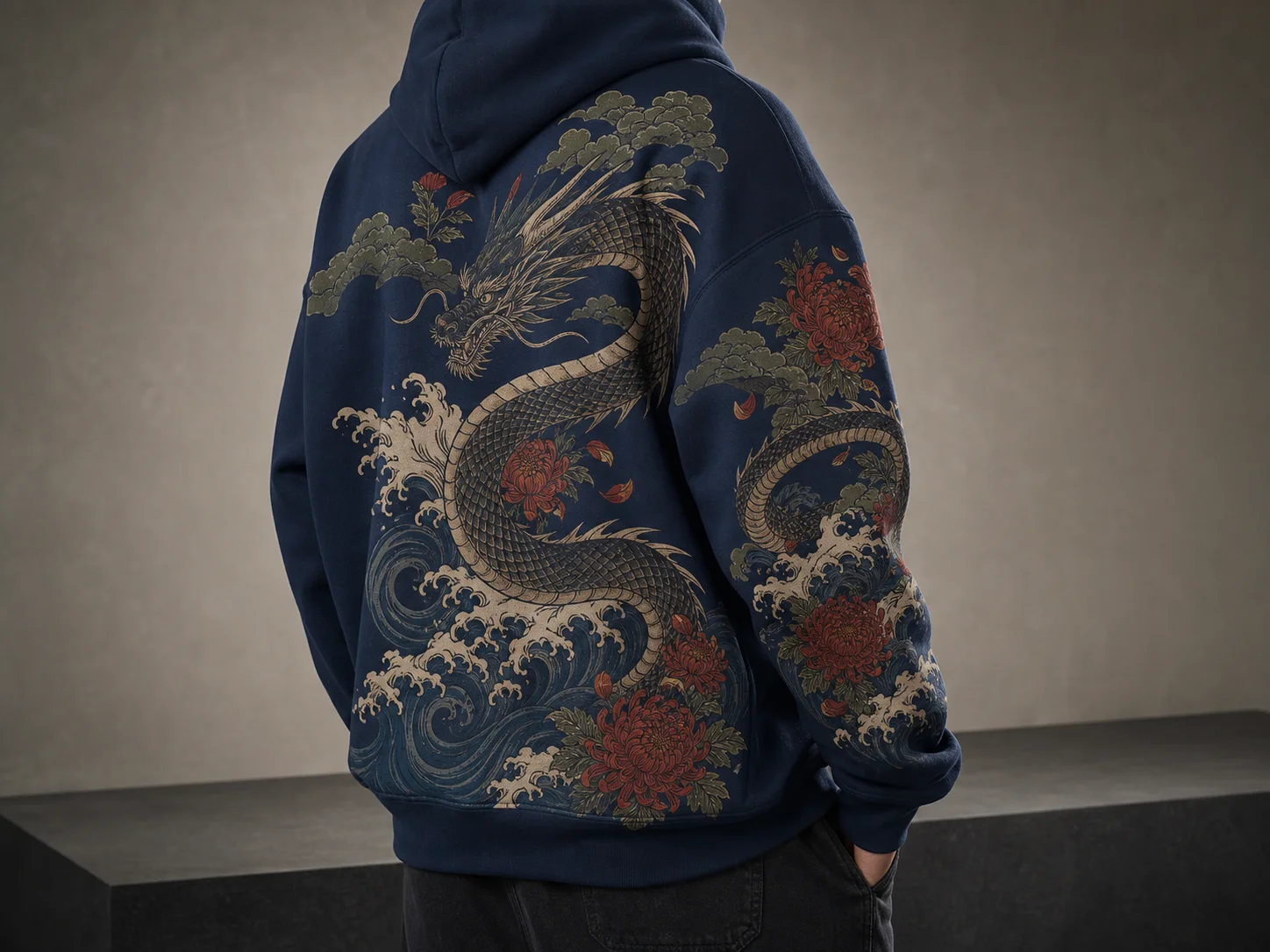 A person wears a navy hoodie featuring an intricate dragon design with waves and flowers, standing against a neutral background.